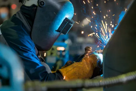 Close-up of a welder wielding sparks . Welder Welding Metal In Workshop