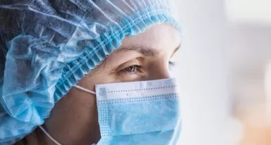 Female doctor in a medical mask and a protective cap